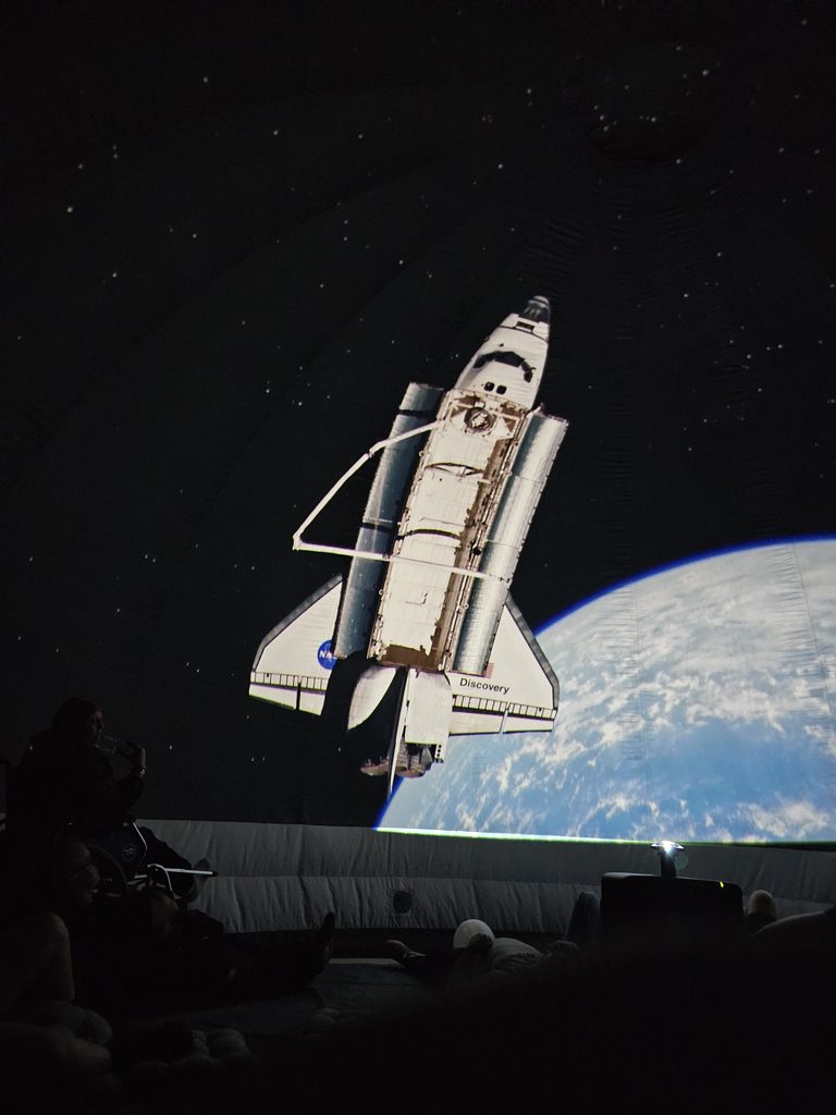 Transbordador espacial Discovery orbitando la Tierra en la proyección fulldome