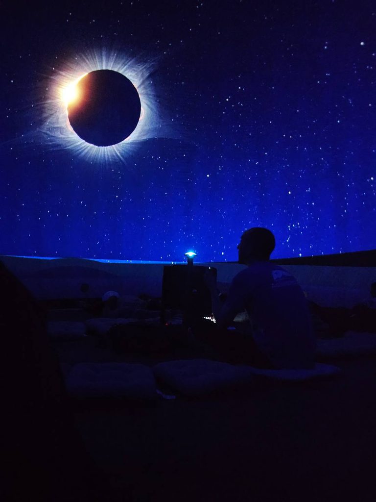 Eclipse solar total proyectado en la cúpula del planetario móvil mientras el astrónomo guía la sesión